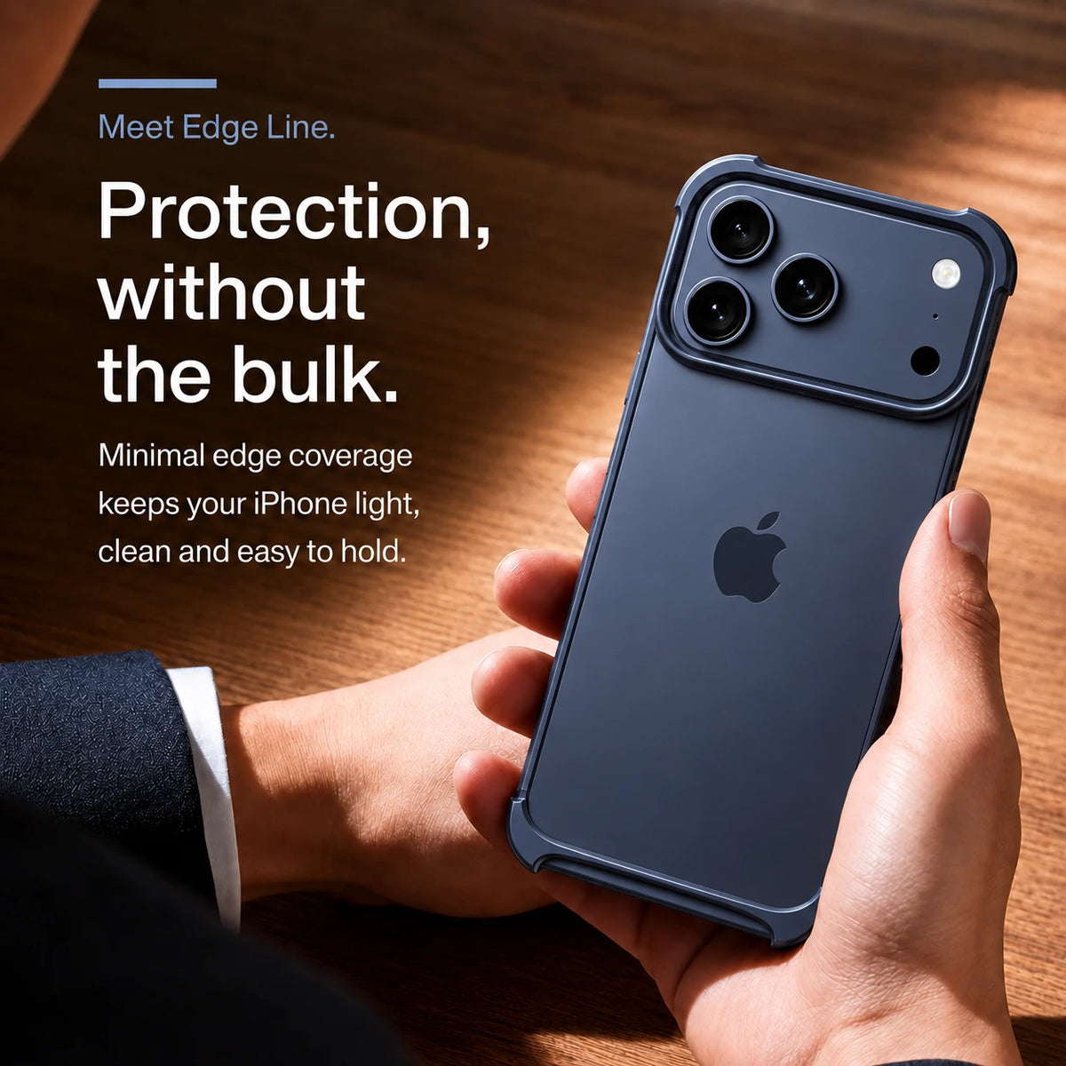 Navy blue open metal bumper phone case held above a wooden desk #color_Deep Blue